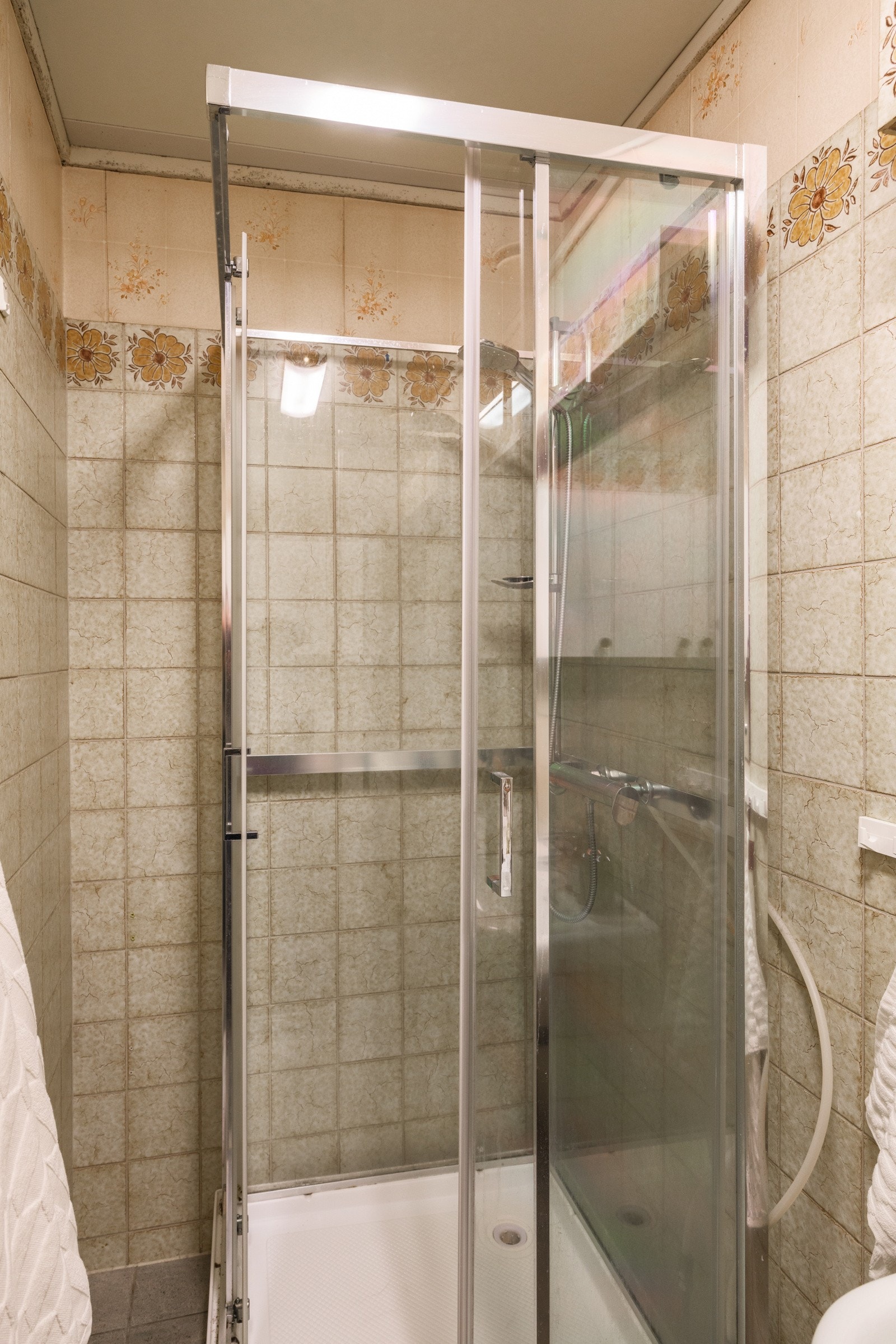 Eldre baderom med fliser på gulv og vegger. Overflater bærer preg av elde og slitasje, og må oppgraderes for å tåle normal bruk etter dagens krav. Galleribilde