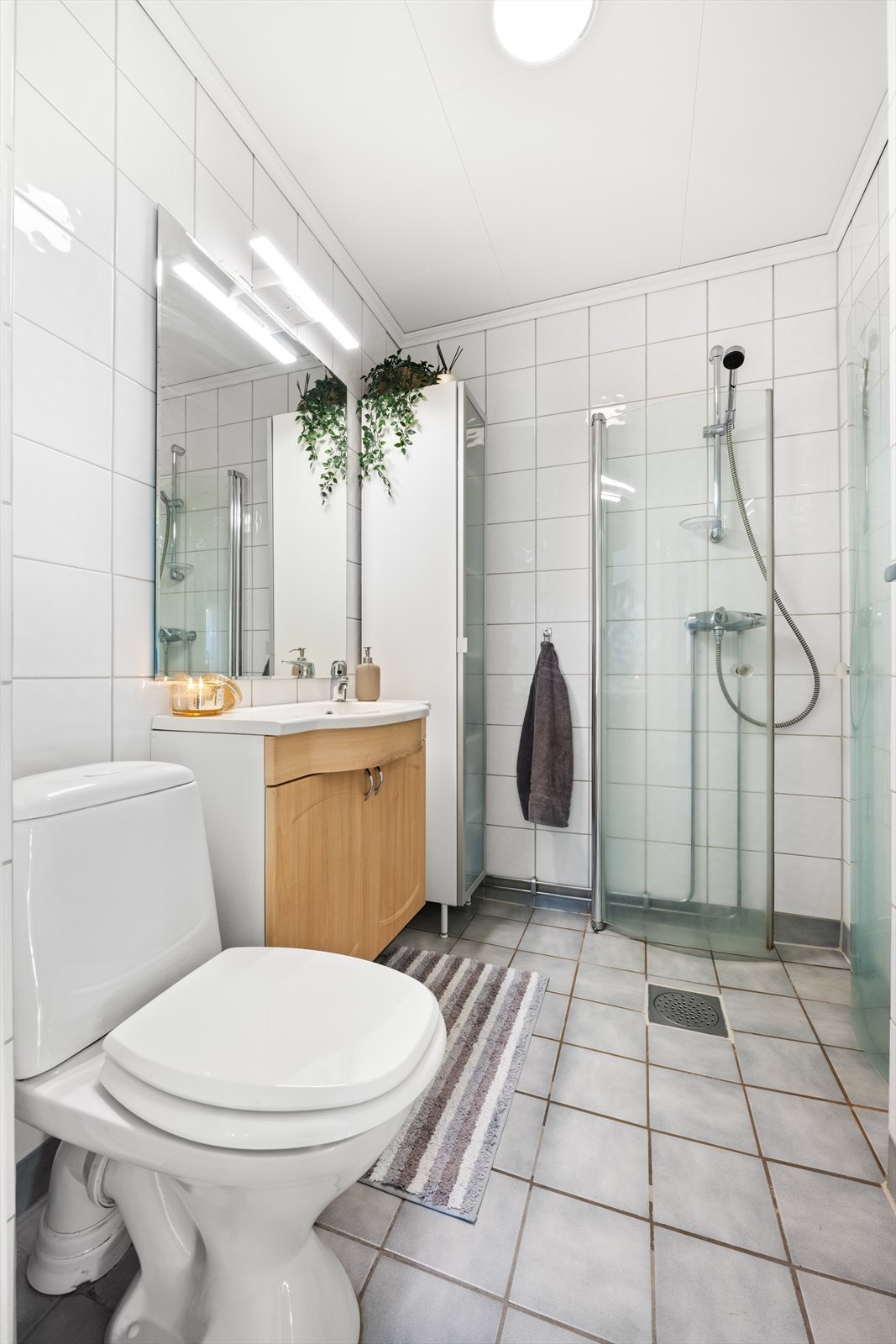 Helfliset bad med varmekabler. Badet inneholder nedfelt servant, toalett og dusjvegger/hjørne. Galleribilde