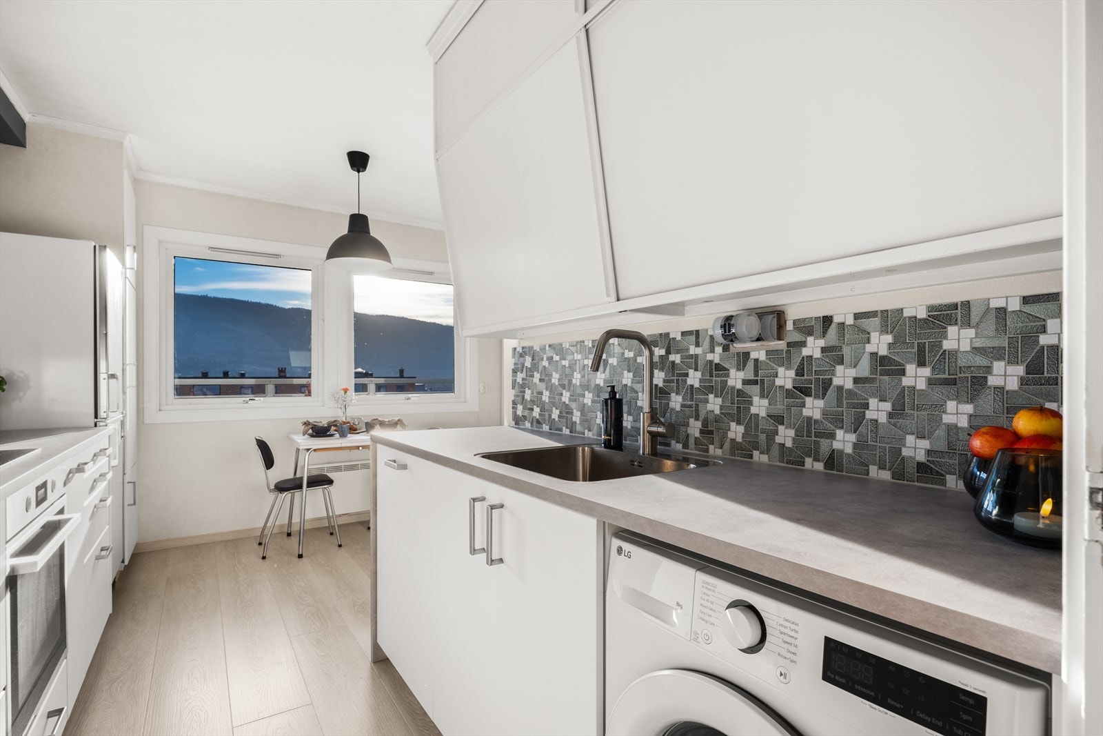 Kjøkkenet har hvite glatte fronter. Benkeplaten er av laminat. Det er opplegg for vaskemaskin på kjøkkenet. Galleribilde