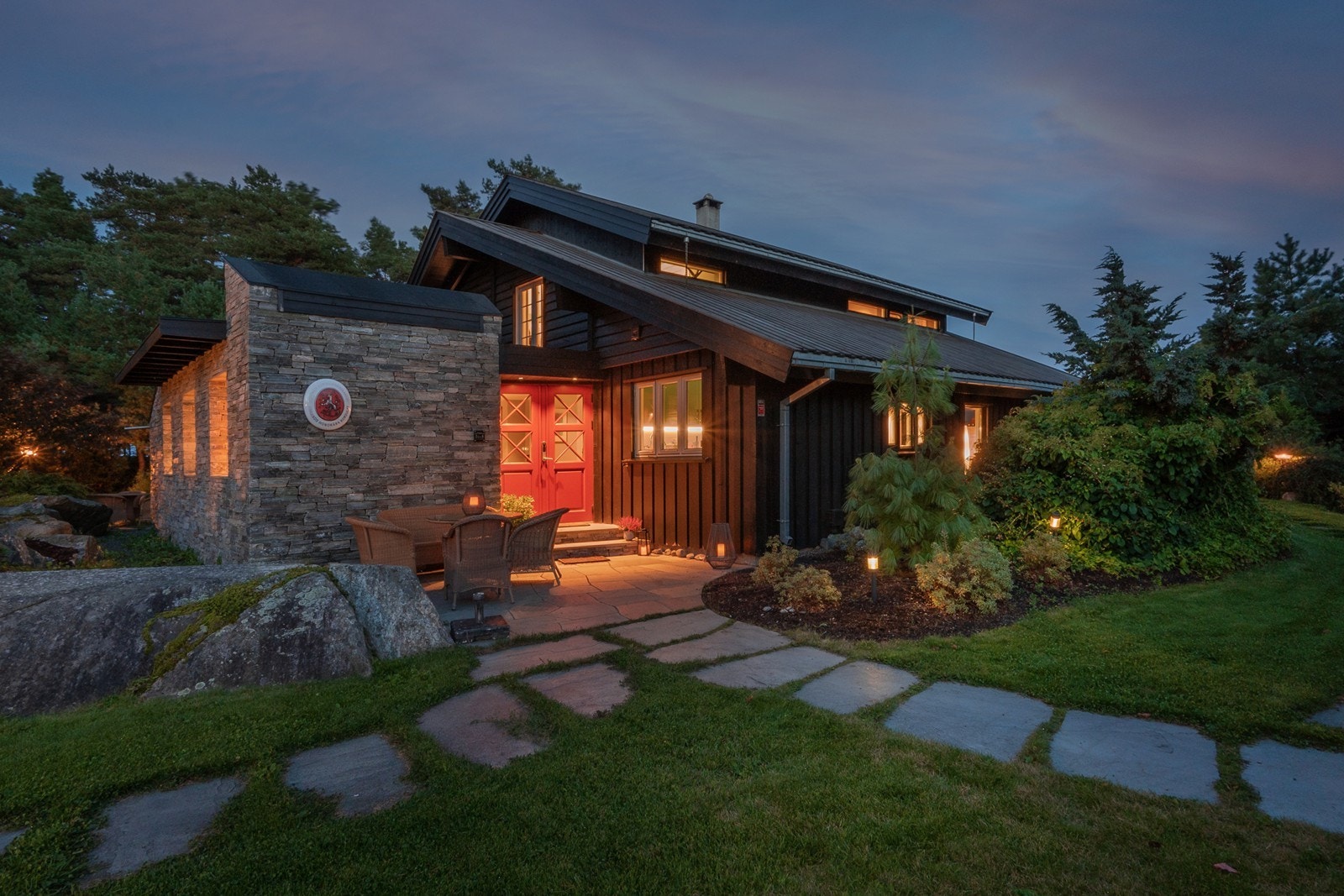 Boligen har et innbydende inngangsparti med skiferheller og plass til sittegruppe. Her kan man nyte både morgenkaffen og lune kvelder, omgitt av vakker beplantning og stemningsfull belysning. Galleribilde