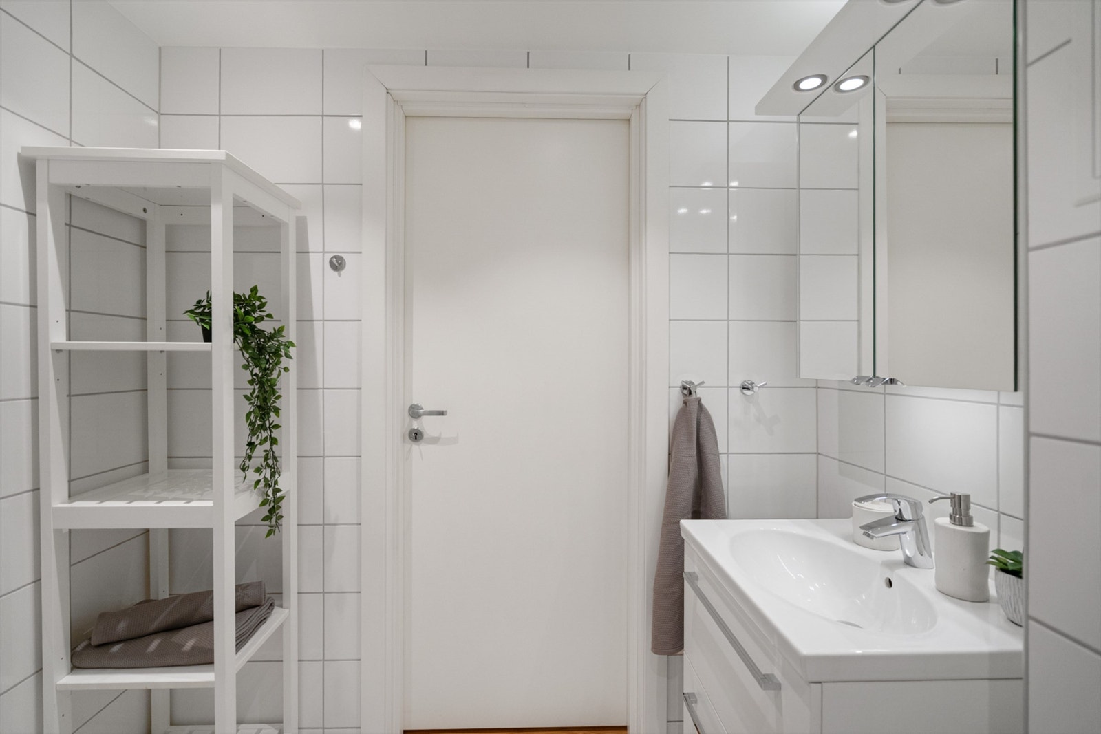 Rommet er utstyrt med dusjhjørne med innfellbare glassdører og har opplegg for vaskemaskin. Galleribilde