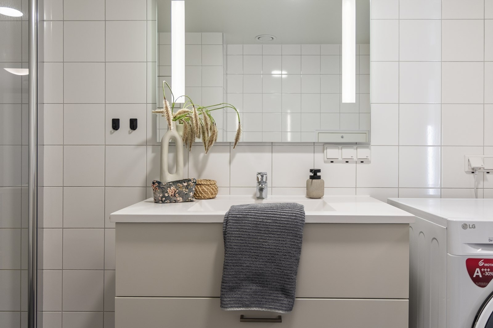 Lys og moderne baderomsinnredning med gode skuffer, servant og speil med innebygget belysning. Galleribilde