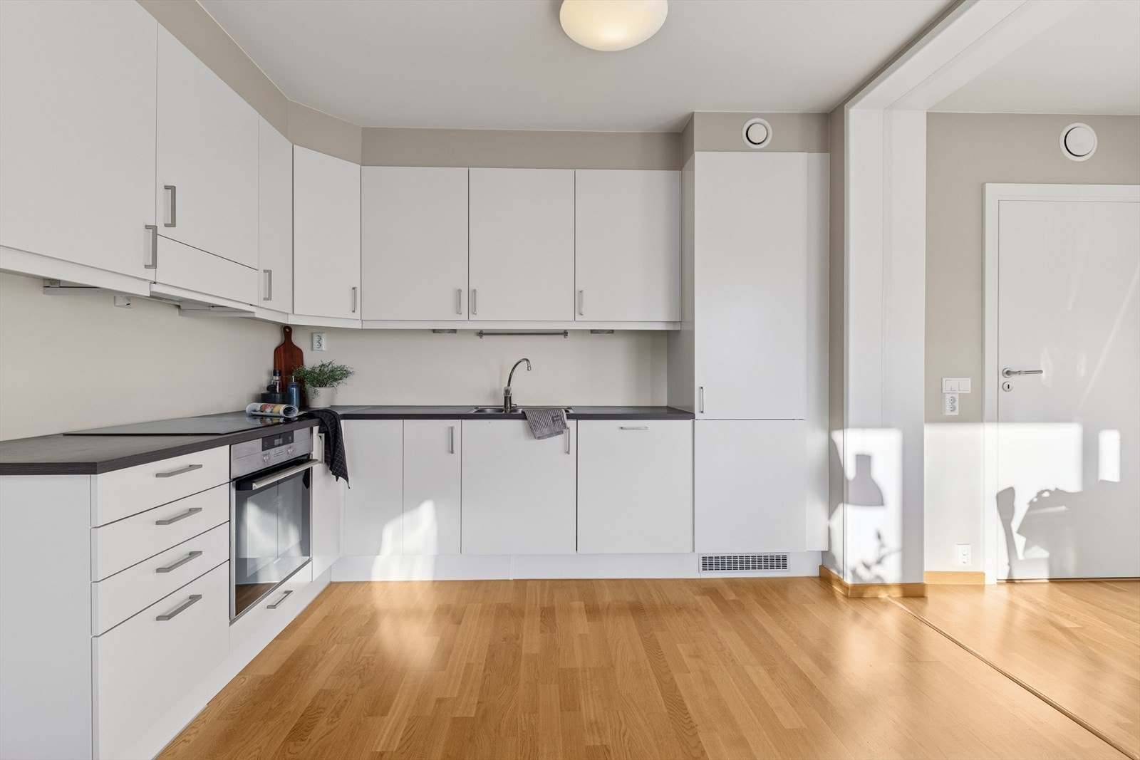 Lyst og stilrent kjøkken med slette fronter og benkeplate av typen laminat. Galleribilde