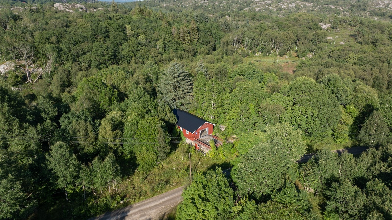 Lagerbygg (brukt som hytte). Parkering ved veien. Galleribilde