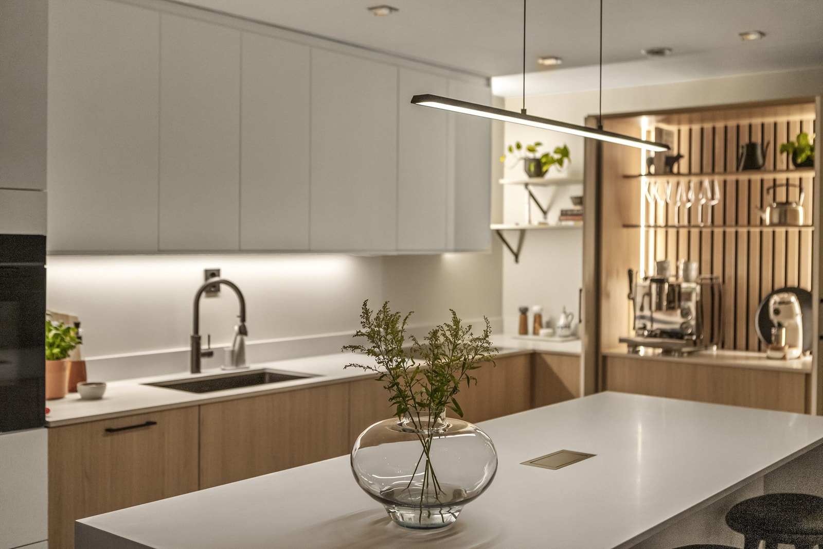 Lekker, hvit benkeplate av kompositt med integrert ladepunkt på kjøkkenøy Galleribilde