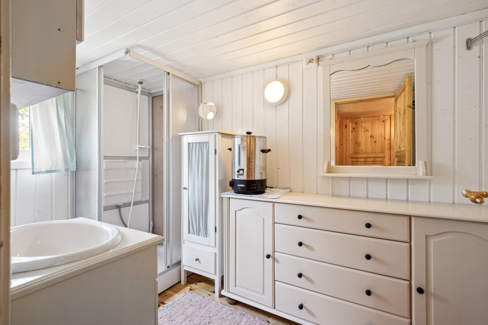 Sanitærrommet har dusjkabinett med fotpumpe og god skapplass, praktisk for hytteliv uten innlagt vann. Galleribilde