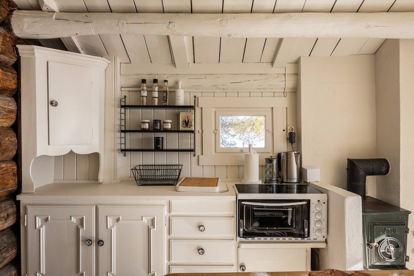 Et hyggelig rom innredet spiseplass med vedovn, kjøkkenbenk og utslagsvask. Galleribilde