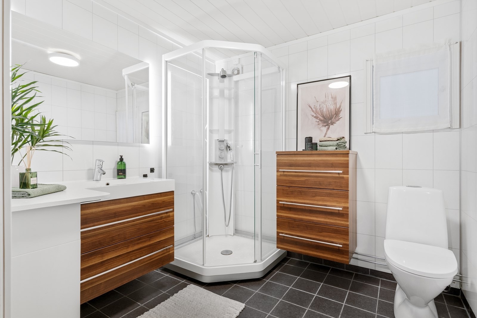 Bad i 1.etasje med flislagt gulv med gulvarme, baderomsplater på vegg og moderne innredning. Galleribilde