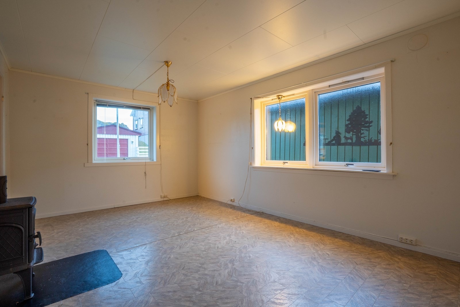 Her er stuen i boligen , trivelig liten stue med vedovn. Vindu som vender mot gaten og mot garasjen som står på eiendommen. Galleribilde