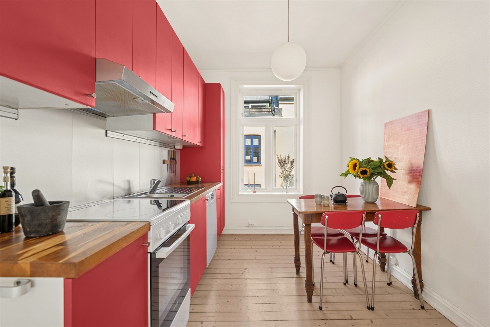 Separat kjøkken bestående av kjøkkeninnredning med malte slette fronter, overskap og stålplater på vegg, heltre benkeplate med nedfelt stålkum og ett-greps armatur i krom. Galleribilde