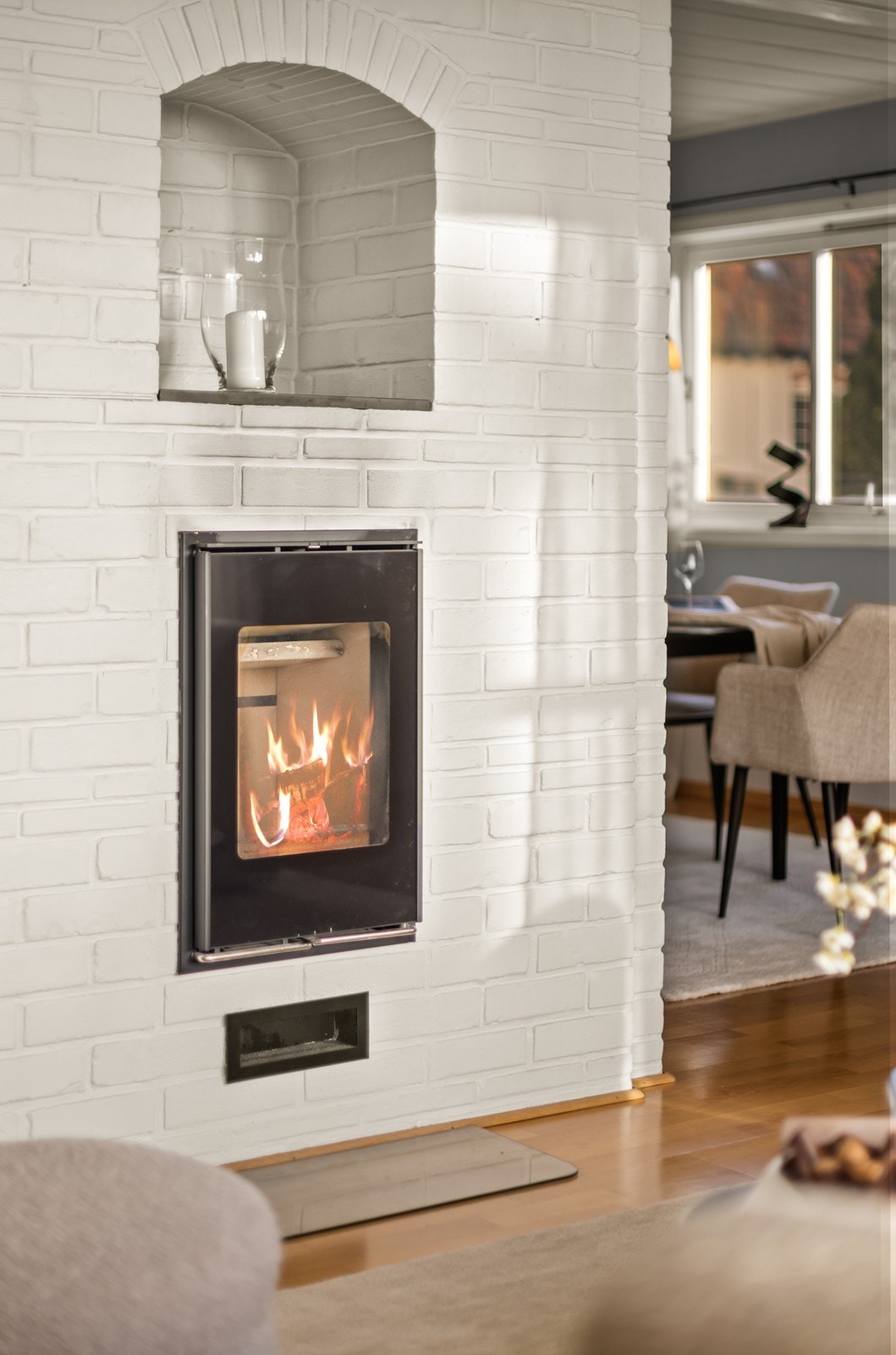 Vedovn er integrert i en pusset teglsteinspipe, som gir både varme og en estetisk detalj til rommet. Galleribilde