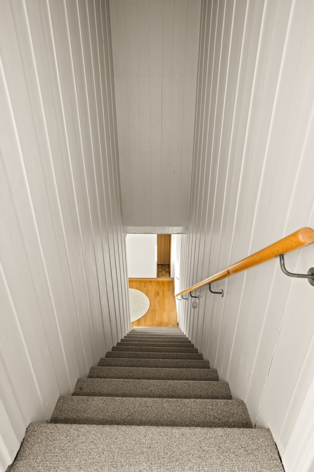 Teppebelagt trapp leder til andre etasje, med åpninger i rekkverk større enn dagens krav (kilde: tilstandsrapport). Galleribilde