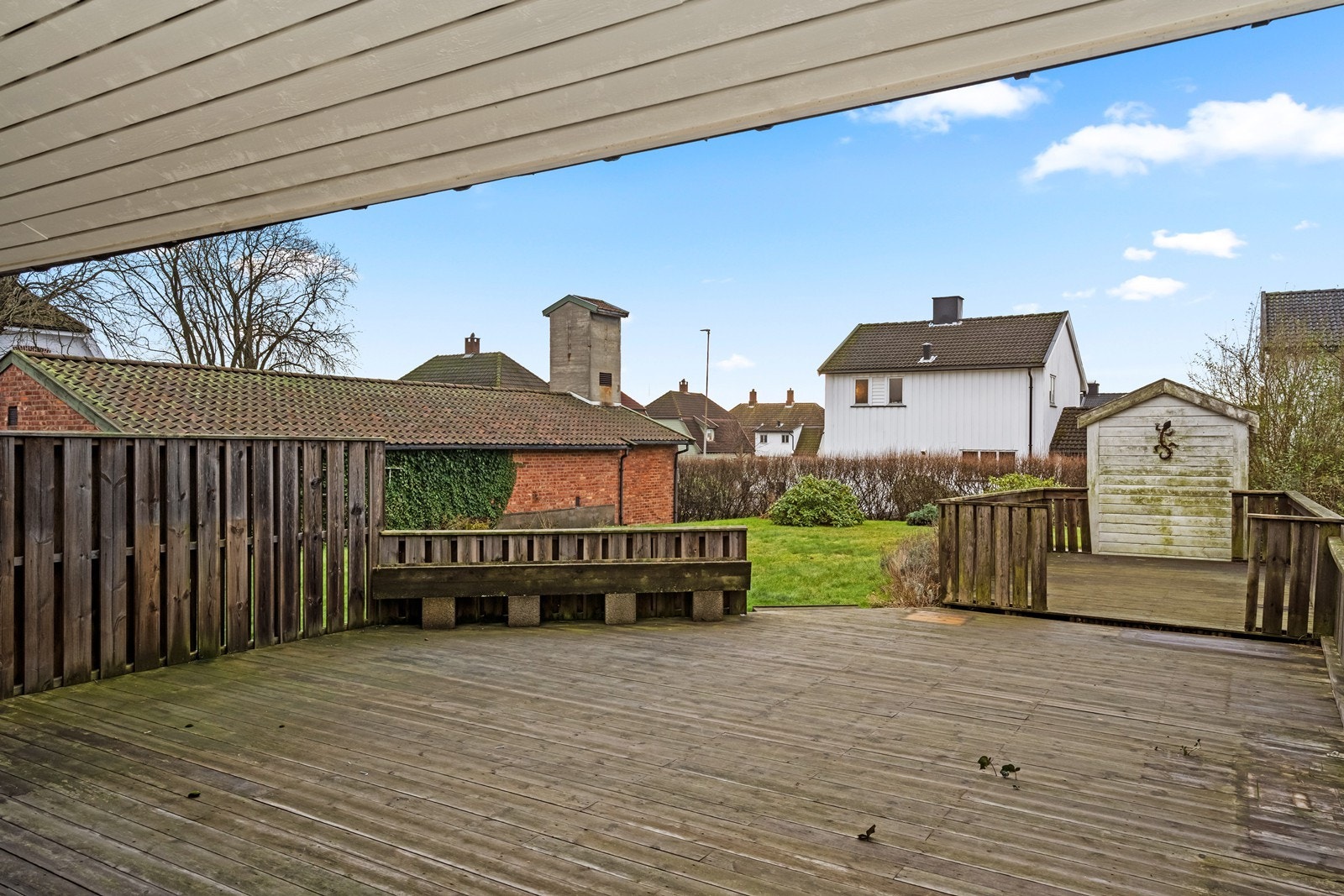 Terrasse med tredekke gir en romslig uteplass. Flat opparbeidet tomt med gressplen og beplantning. Galleribilde
