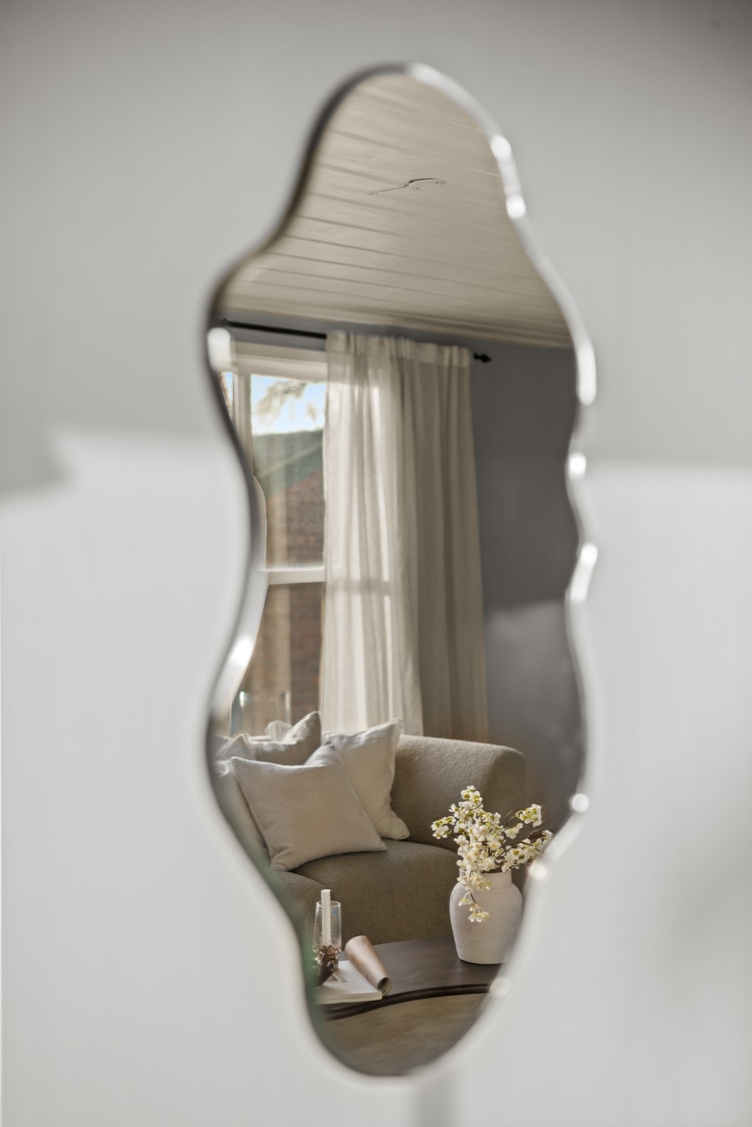 Speil reflekterer lys fra stuen, som har parkettgulv og malte vegger. Galleribilde