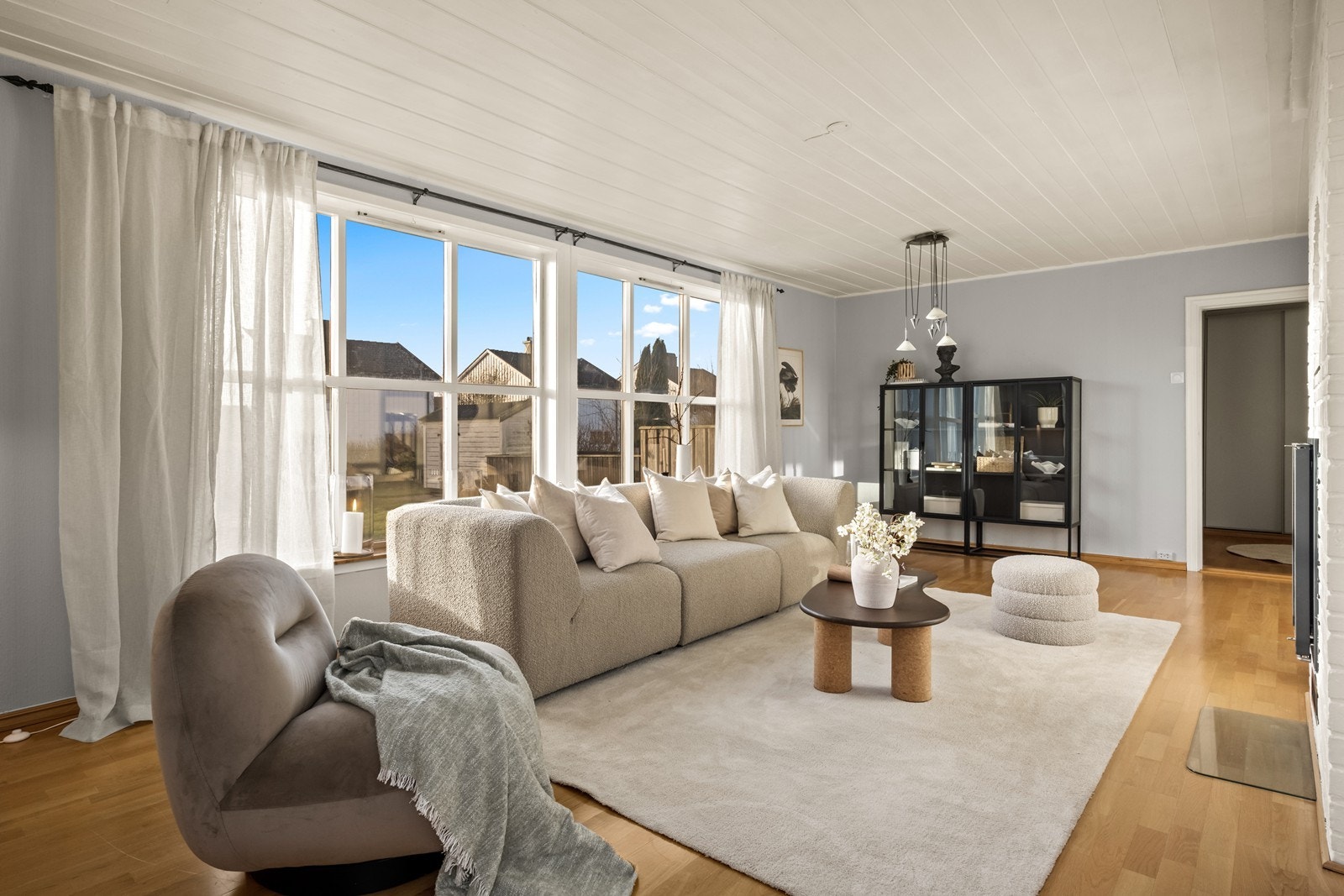 Store vindusflater gir rikelig med naturlig lys til stuen, som har parkettgulv og malte vegger. Galleribilde