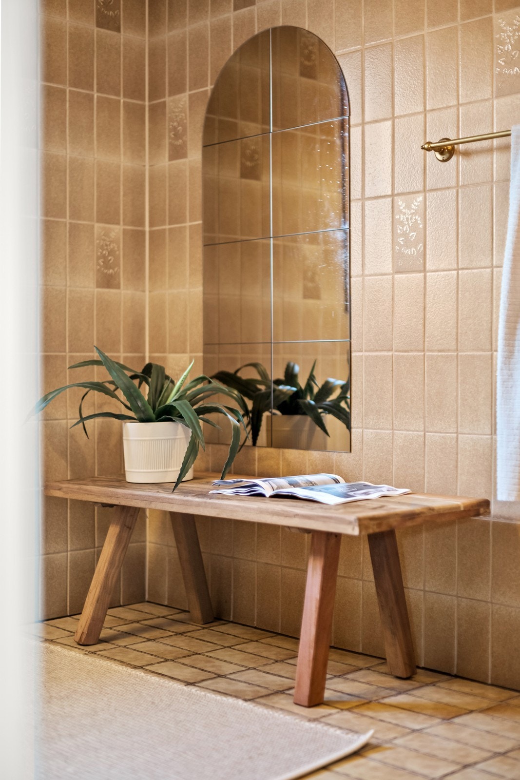 En benk med planter gir dekorativt preg til badet, som har flislagte vegger. Galleribilde