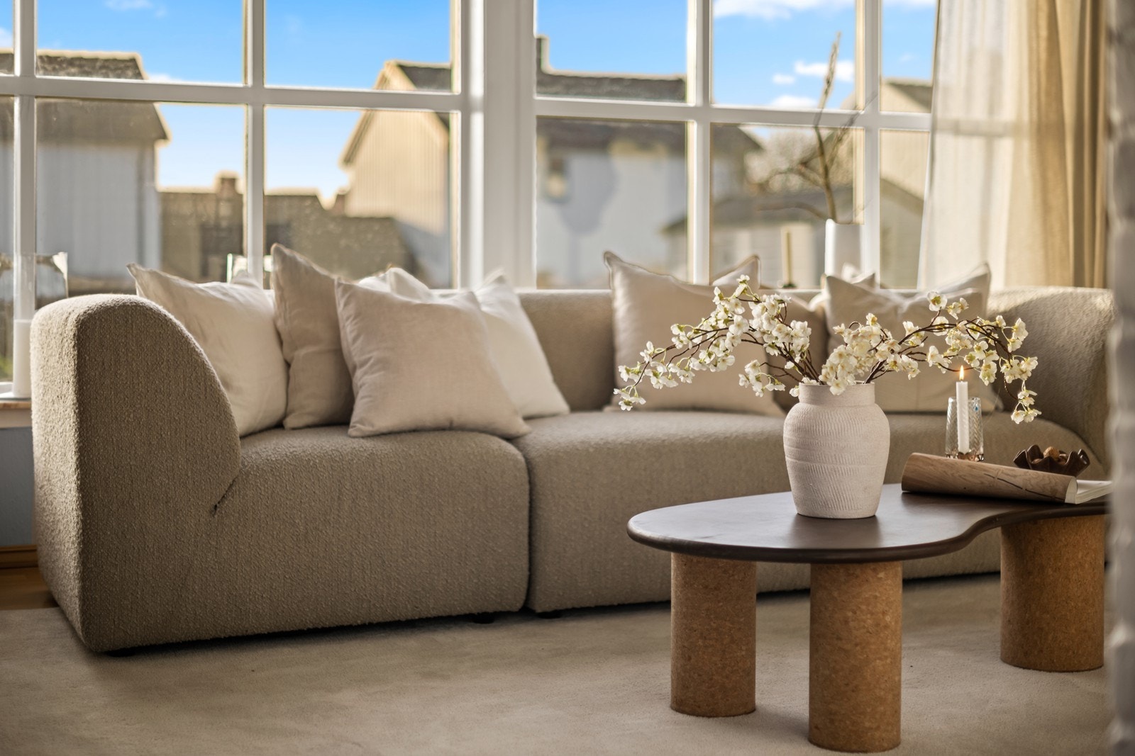 Utsyn mot grøntområde og nabohus fra stuen, som har parkettgulv og malte vegger. Galleribilde