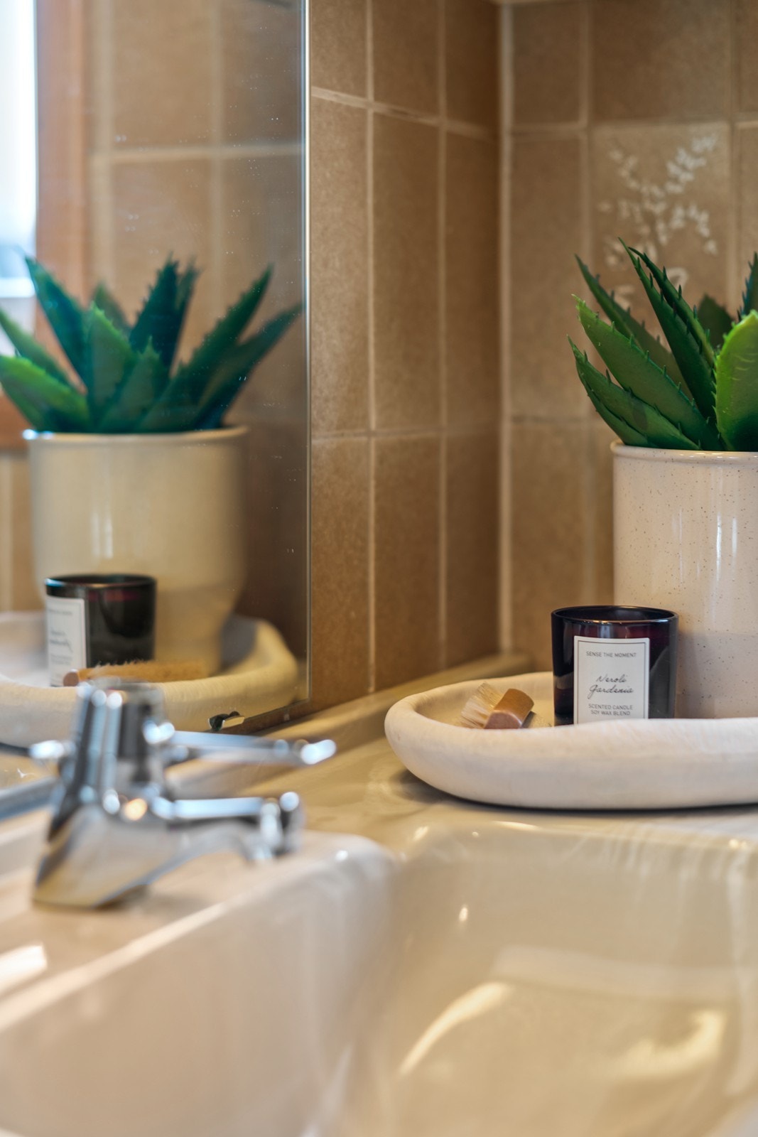 Servanten er plassert under et stort speil, og badet har fliser som viser tegn til alder. Galleribilde