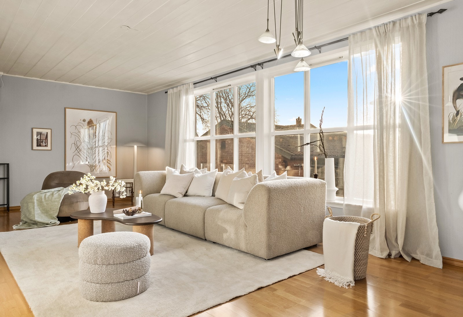 Parkettgulv og malte vegger preger stuen, mens store vinduer gir utsyn mot hageområde. Galleribilde