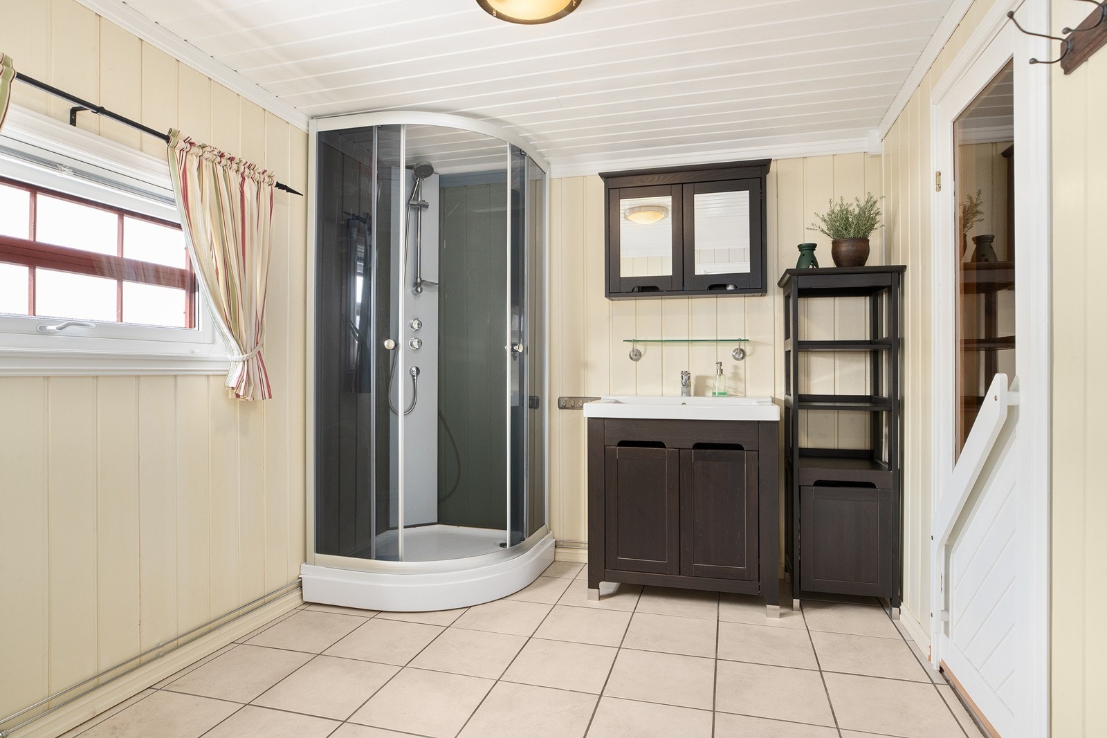 Baderom med flis på gulv, dusjkabinett og servant med skap Galleribilde