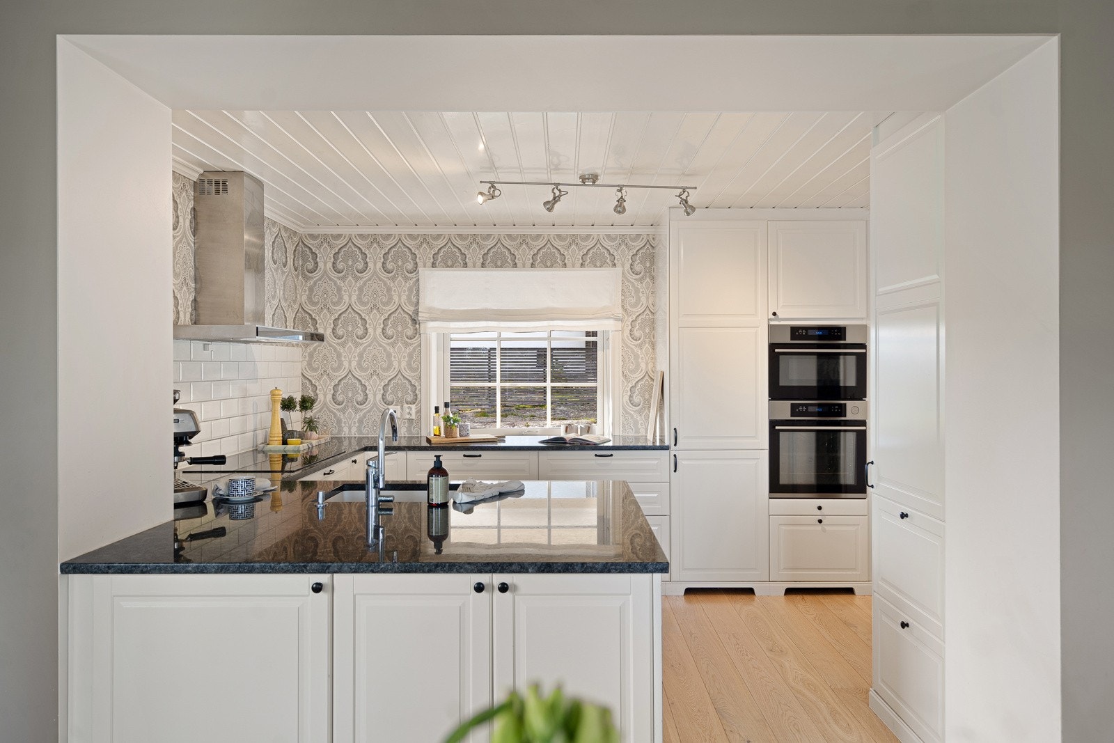 Kjøkkenet ligger i tilknytning til stuen og har en pen innredning med profilerte fronter og benkeplate i stein Galleribilde