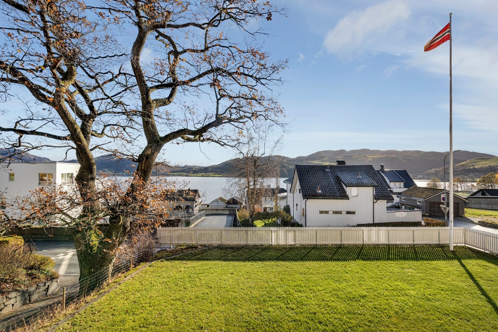 Hage - hvitt stakittgjerde, grønt plen og klassisk hus Galleribilde