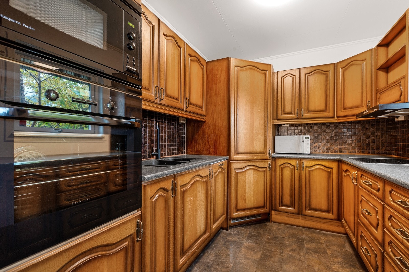 Kjøkkeninnredningen har innebygde hvitevarer som kjølehjørne, mikro, stekeovn, koketopp og oppvaskmaskin Galleribilde