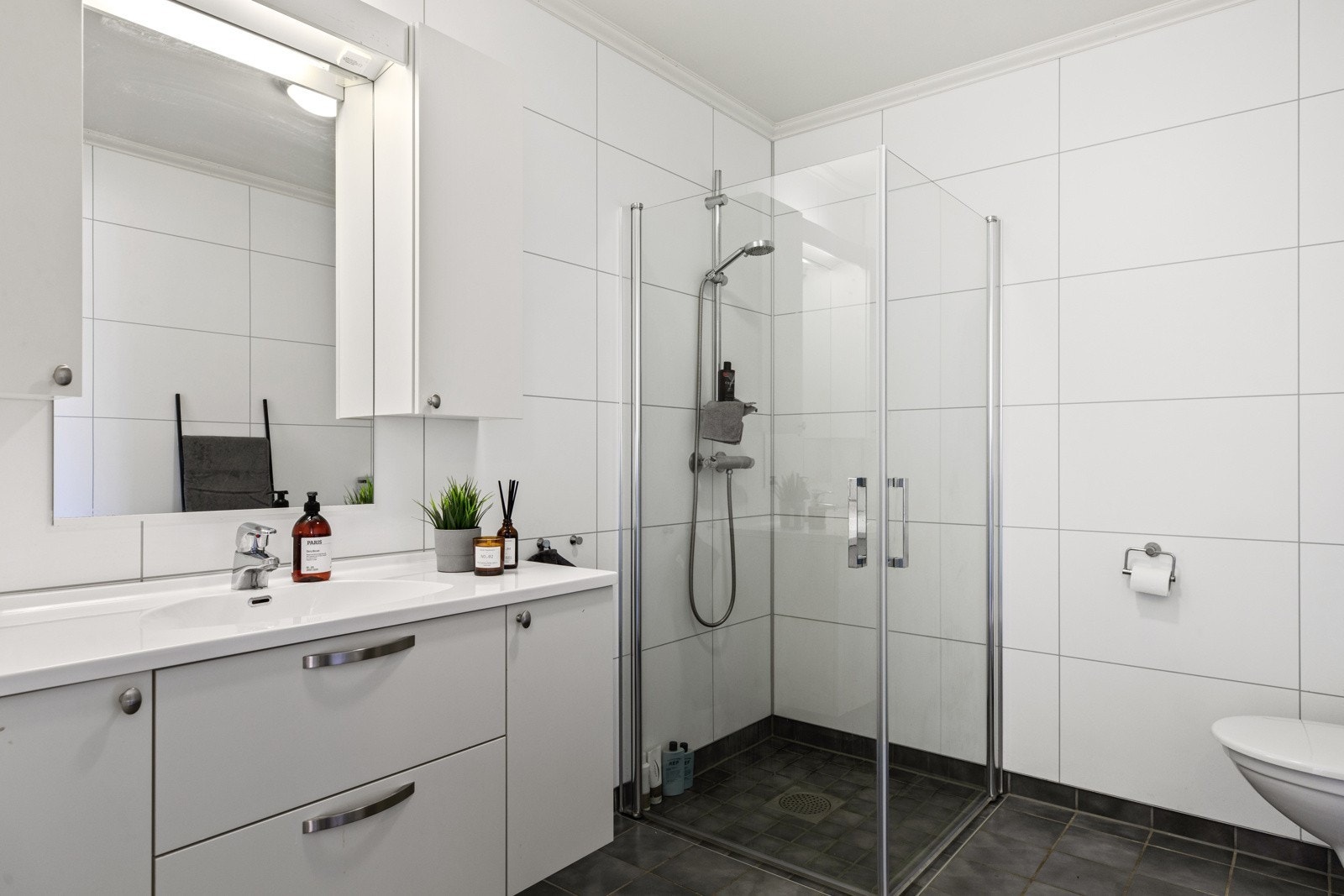 Pent flislagt bad med innfellbare dusjdører og godt med skap-plass Galleribilde