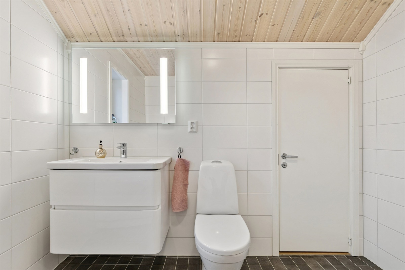 Rommet har flislagt gulv med varmekabler, servantskap og speil med integrert lys. Galleribilde