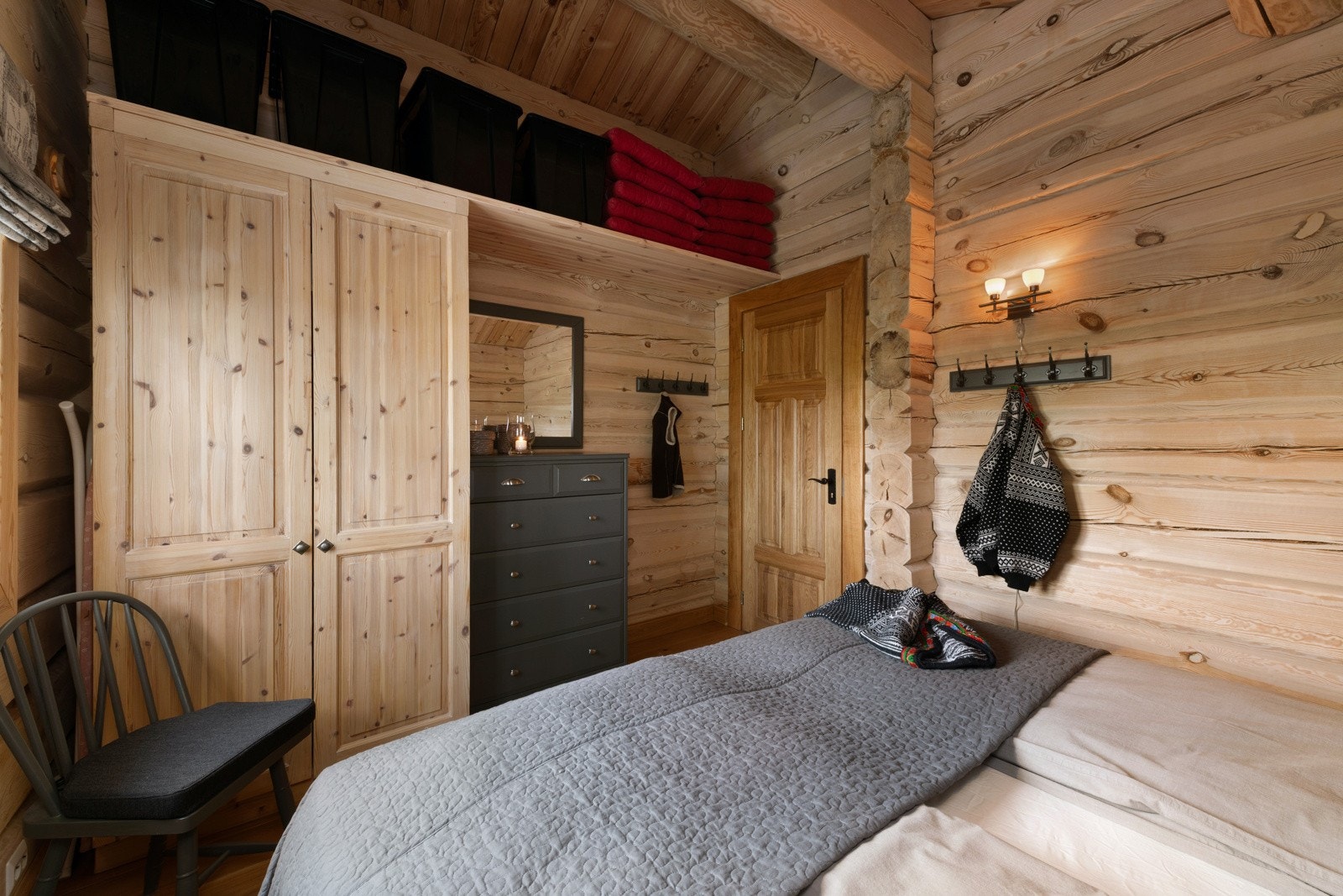 Lyst soverom med trepanel på vegger og tak, garderobeskap og kommode. Galleribilde