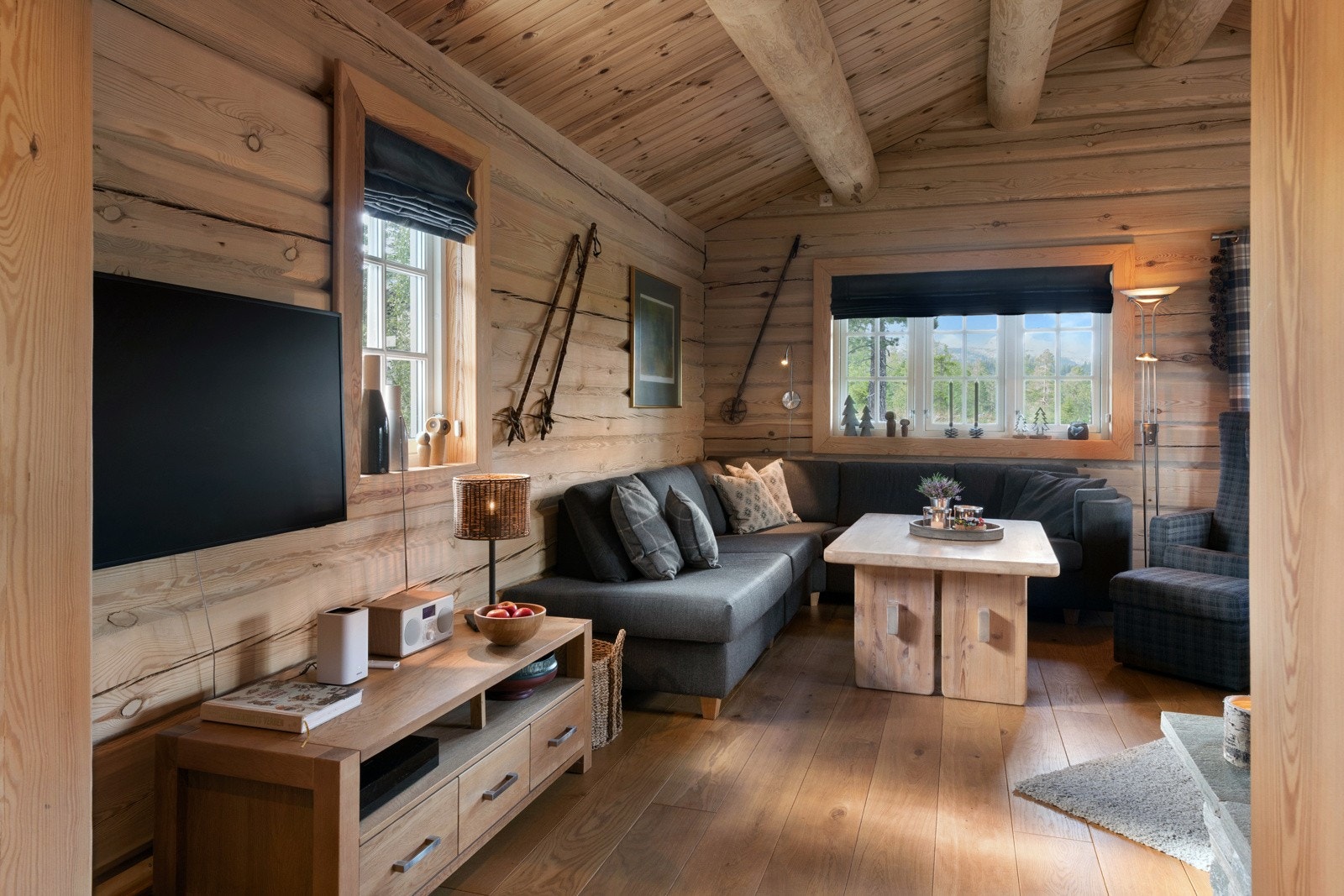 Stue med tømmervegger, takbjelker og store vinduer som slipper inn godt med naturlig lys. Galleribilde