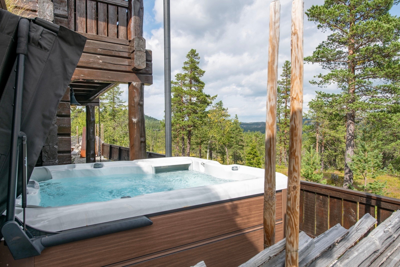 Utendørs boblebad med utsikt mot skogkledd landskap og fjell, perfekt for avslapning og nytelse. Galleribilde