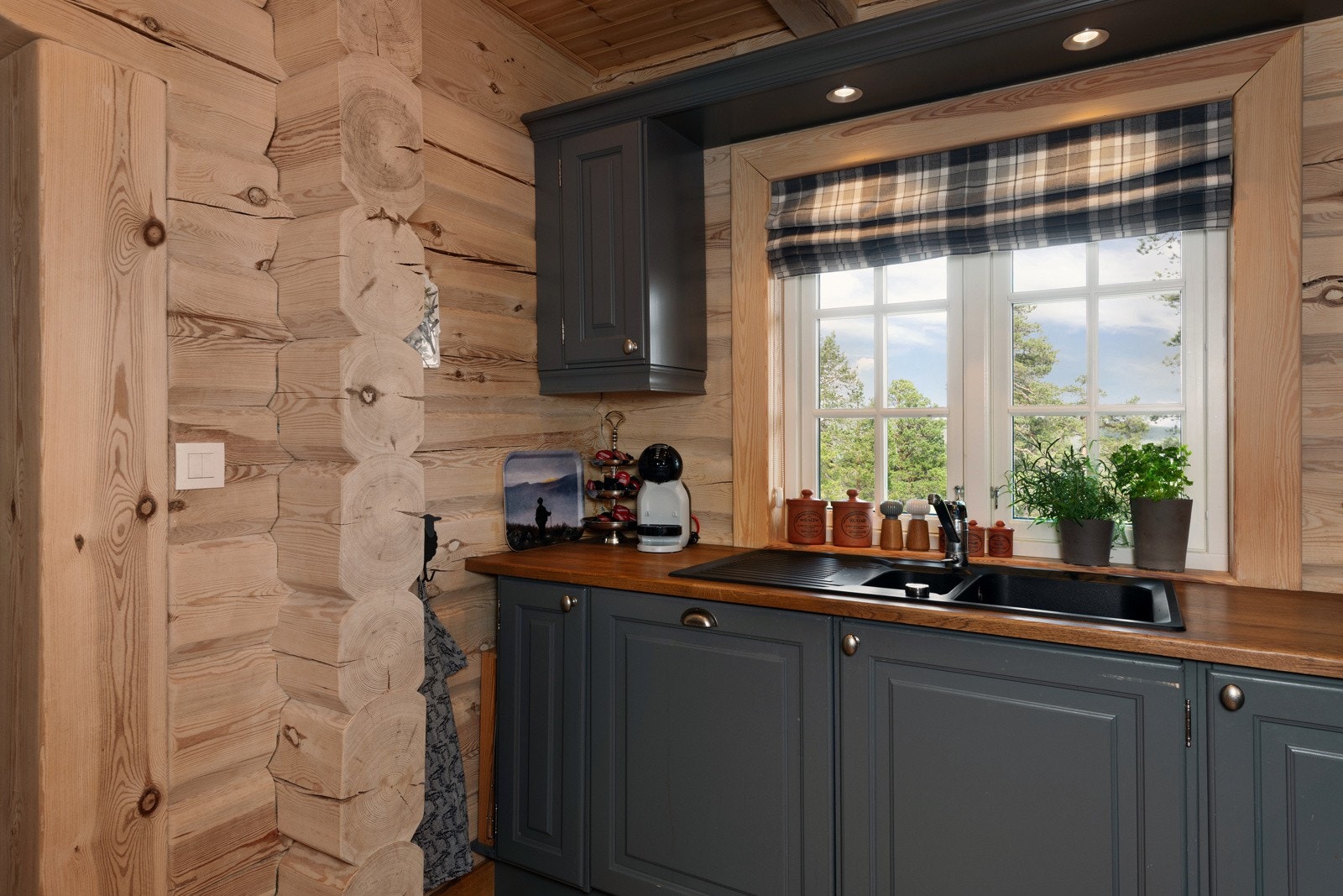 Lyst kjøkken med trevegger, grå innredning og vindu med utsikt. Galleribilde