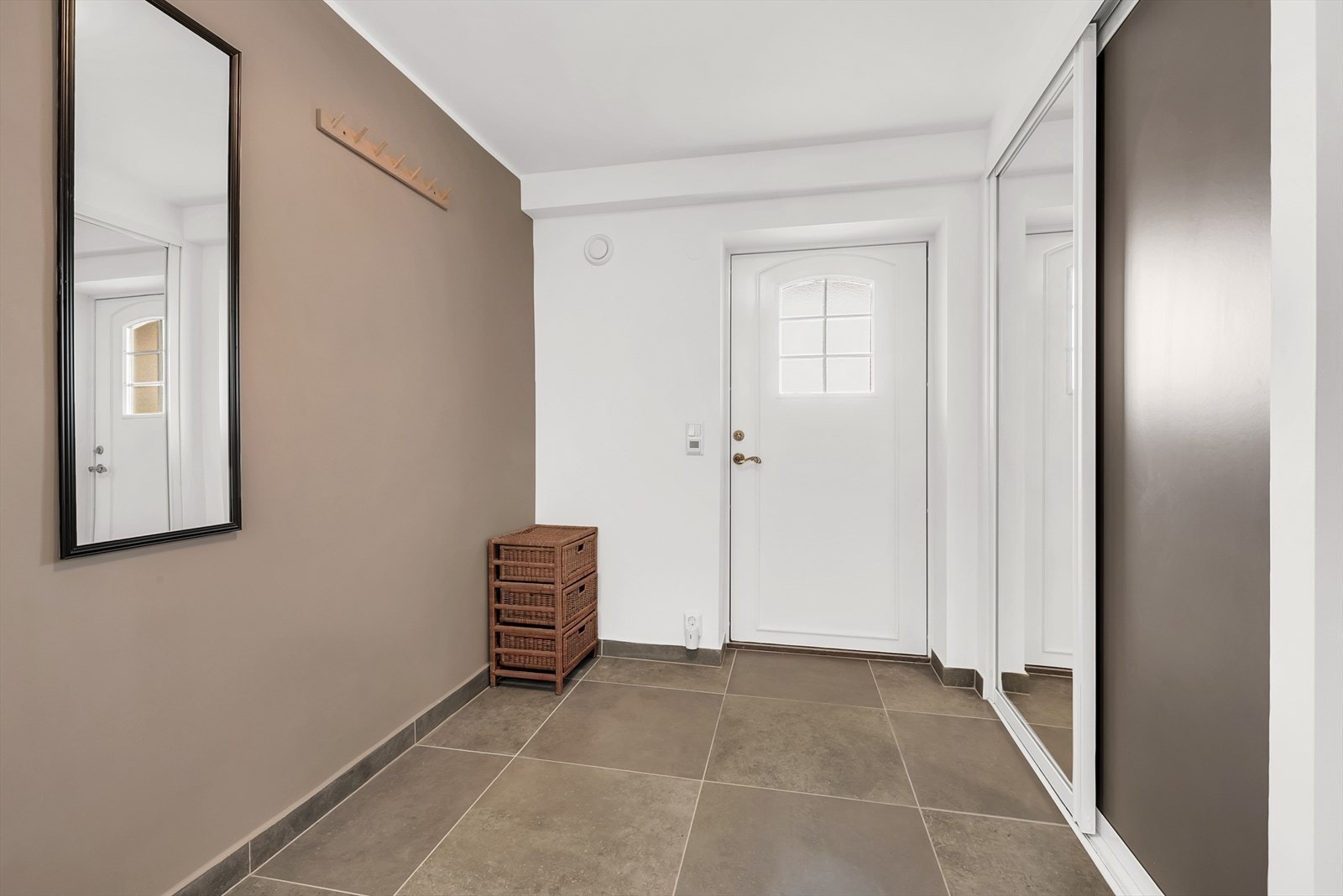 Entre og flislagt gang med varmekabler og god plass for å henge fra seg yttertøy i montert skyevedørsgarderobe. Galleribilde