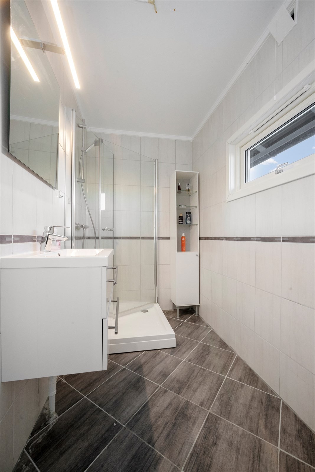 Dette badet ble pusset opp i 2009, med hvite, flislagte vegger og mørkegrå gulvfliser Galleribilde