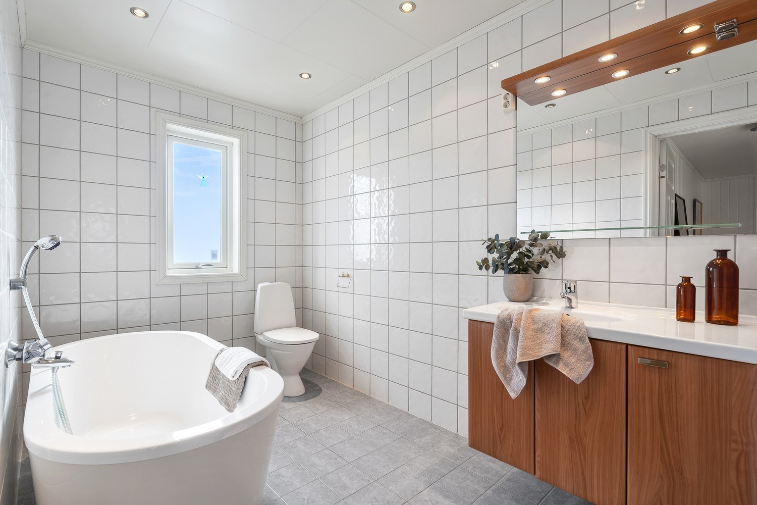 Boligens første bad er fra byggeåret 2008. Det har flislagt gulv med gulvvarme, samt fliser på vegger og takessplater på innvendig tak. Rommet har baderomsinnredning med heldekkende servant og underskap med dører, høyskap, frittstående toalett og badekar. Galleribilde