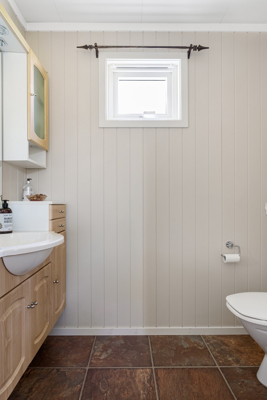 Lyst og lekkert toalettrom med skap med servant. Galleribilde