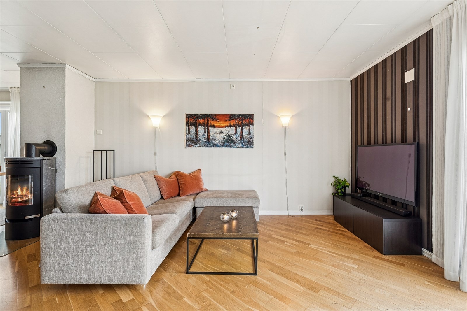 Stuen er et romslig oppholdsrom med parkett på gulvet og et ildsted som bidrar med varme. Galleribilde