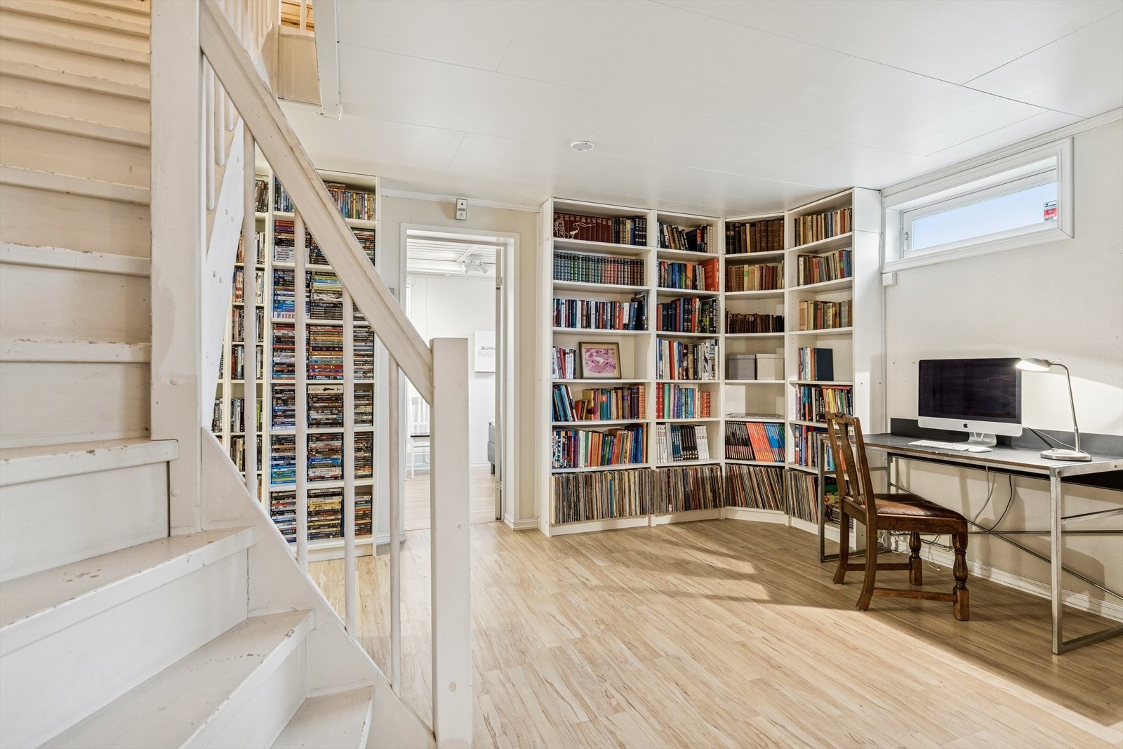 Trapperommet leder ned til et romslig hobbyrom med ildsted og laminatgulv. Galleribilde