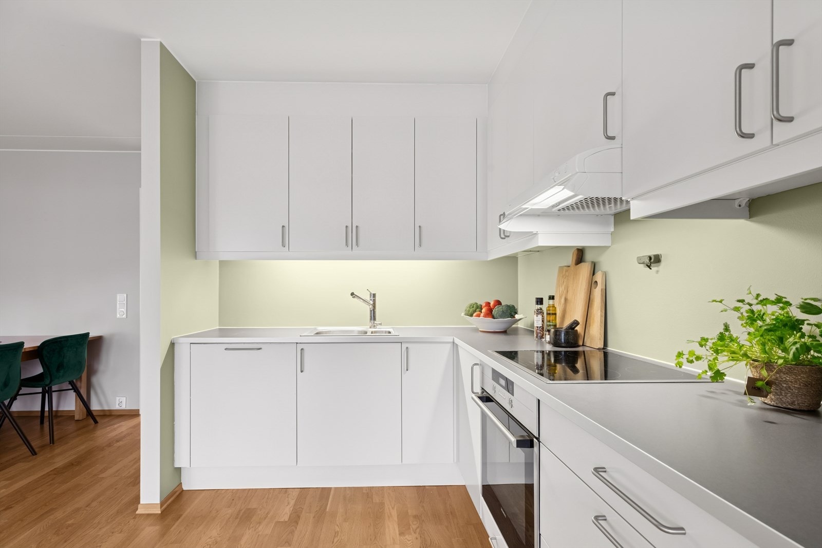 Innredningen har hvite, glatte fronter, skapdører med stålbeslag og en laminat benkeplate med nedfelt oppvaskkum. Galleribilde