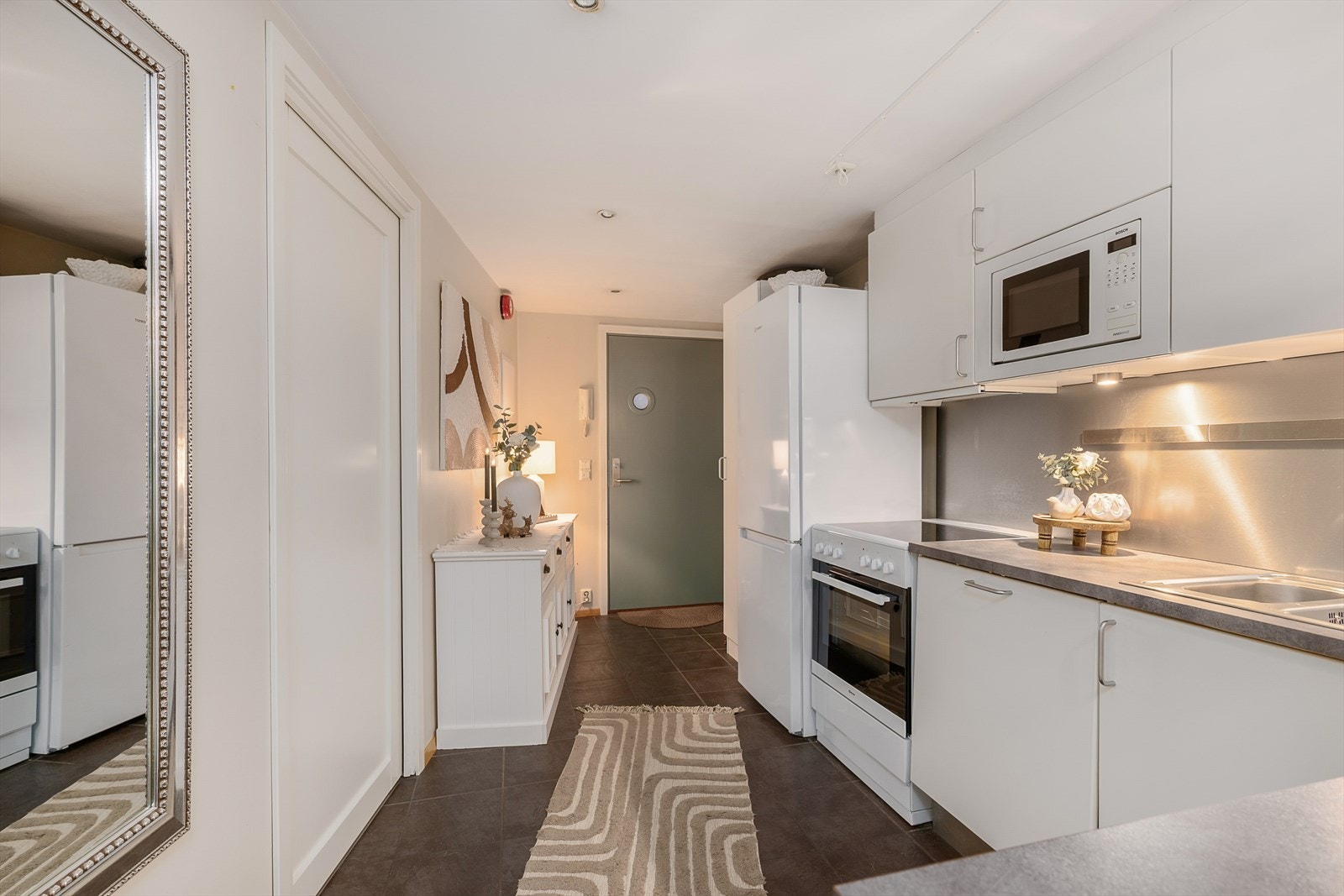 Kjøkkeninnredningen har glatte fronter og plater i børstet stål over benken. Galleribilde