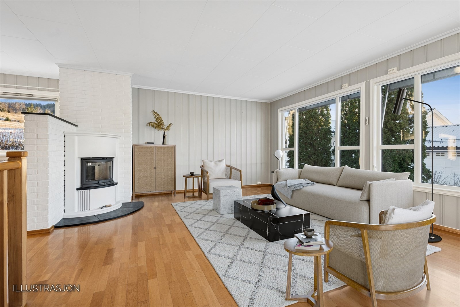 Et sentralt plassert ildsted gir en lun atmosfære og supplerer varmepumpen for effektiv oppvarming. Galleribilde