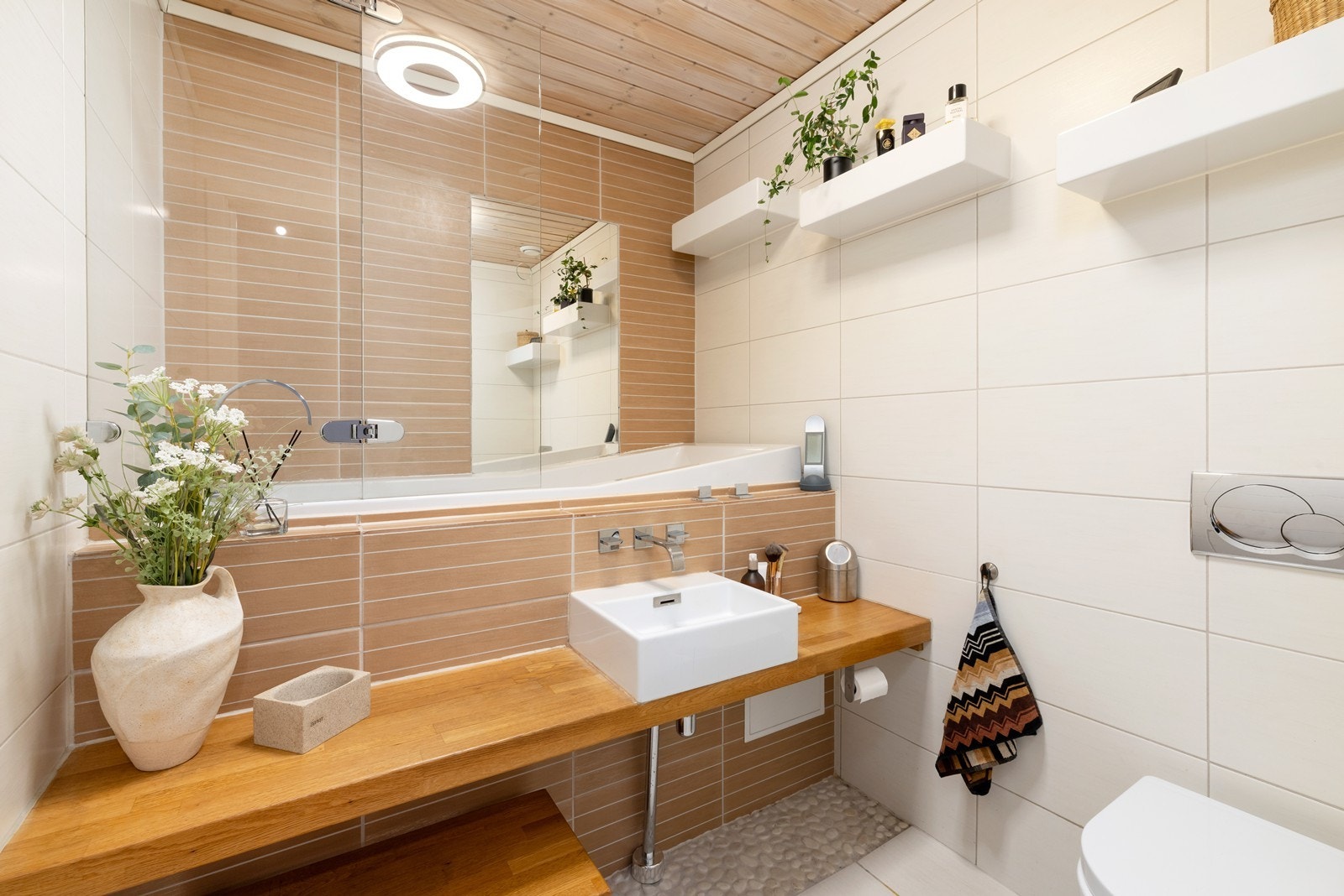 Baderommet er pent flislagt med gulvvarme. Her er det badekar, servant med innredning og vegghengt wc. Galleribilde