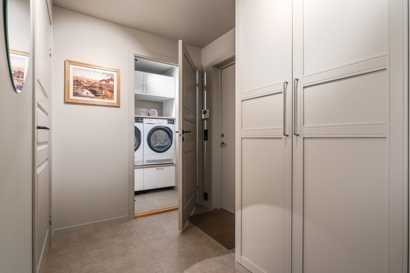 Romslig entre som måler 7 kvm. Her er det satt opp store garderobeskap som gir mye plass for oppbevaring. Vaskerommet i enden er på 2,5 kvm. Smarte hyller til vask og tørk gjør klesvasken enklere. Ellers er det også her mye annen plass for oppbevaring. Va Galleribilde