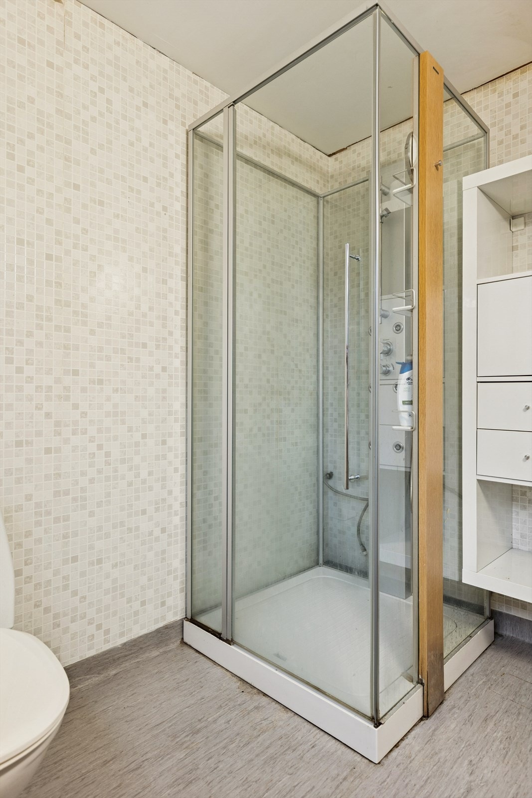 Rommet er innredet med et dusjkabinett, servant og toalett. Belegg på gulvet og våtromstapet på veggene. Galleribilde