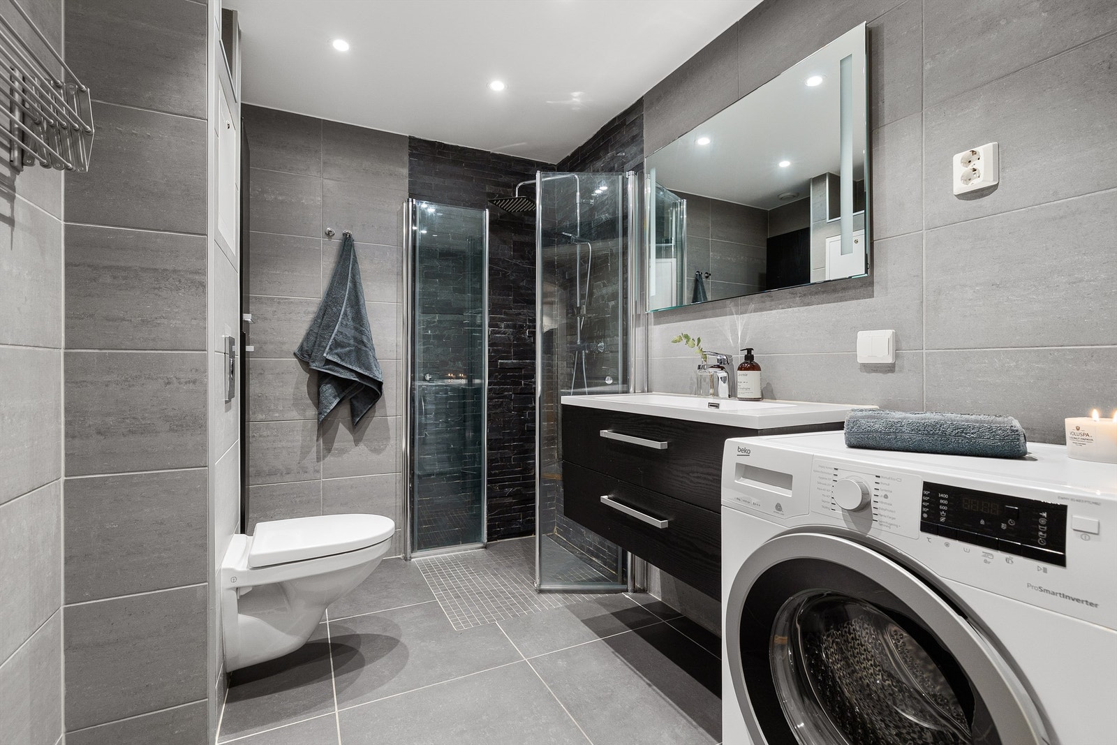 Innbydende og meget romslig bad fra 2019 med grå fliser, varme i gulv og downlights i himling. Opplegg for vaskemaskin Galleribilde