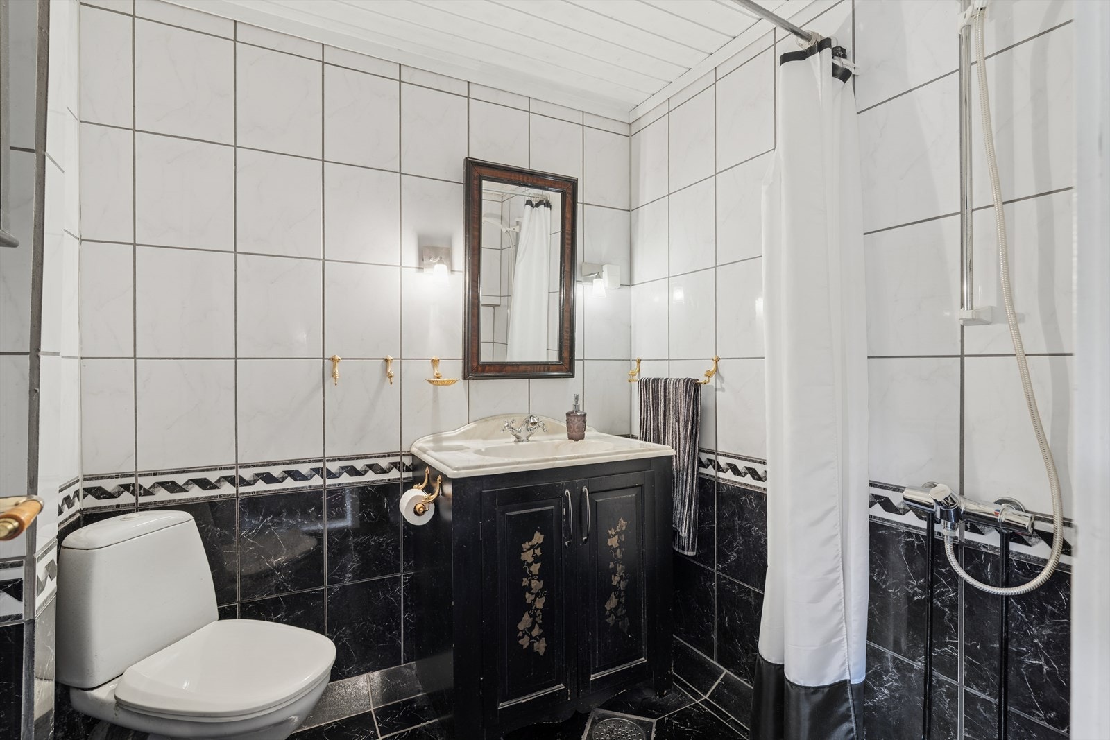 Helfliset baderom med åpen dusj, gulvmontert toalett og servant med skap. Galleribilde