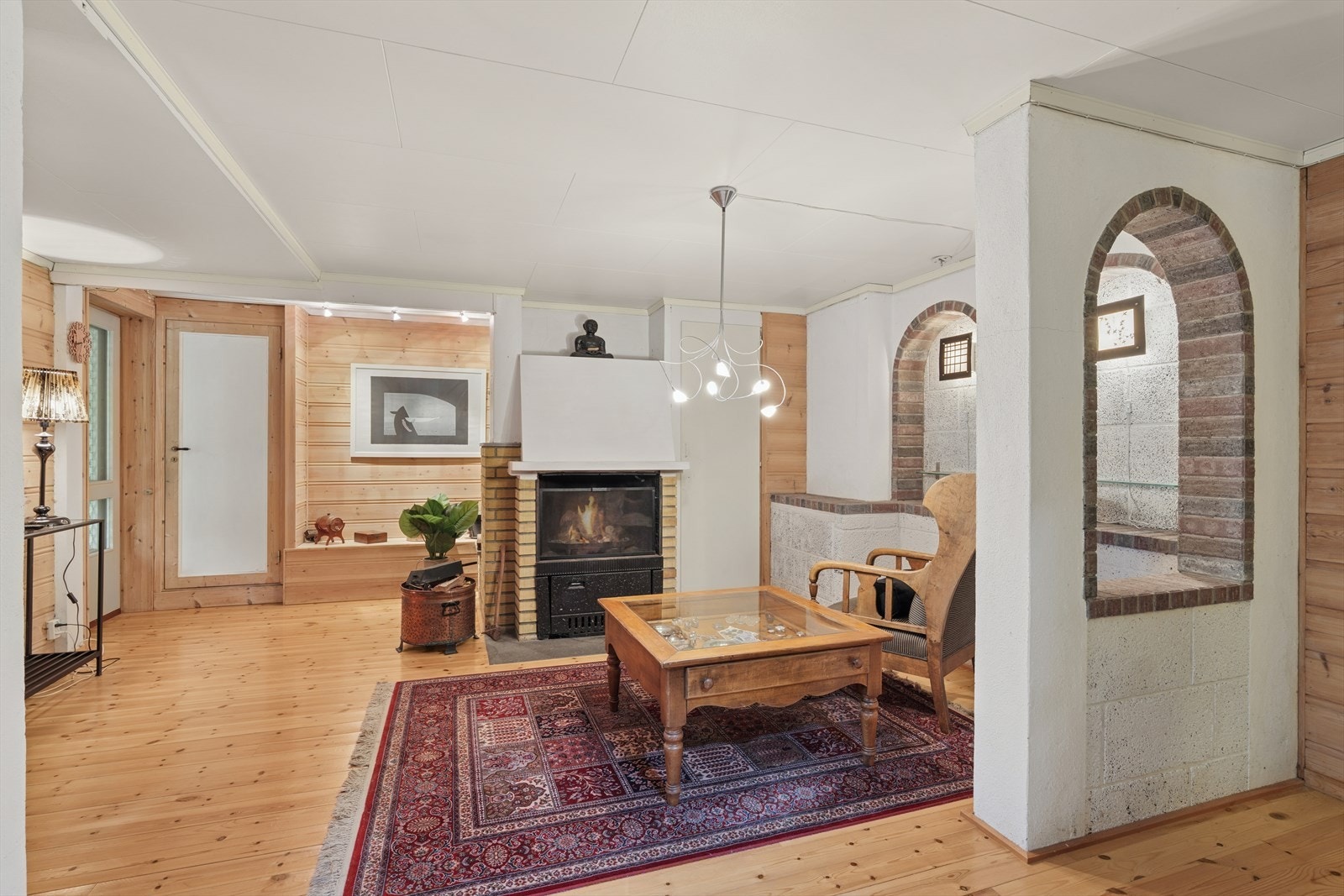 Furugulv og trepanel på vegger gir et naturlig preg til kjellerstuen. Vedovnen skaper en varm atmosfære og er plassert i en mursteinsnisje. Galleribilde