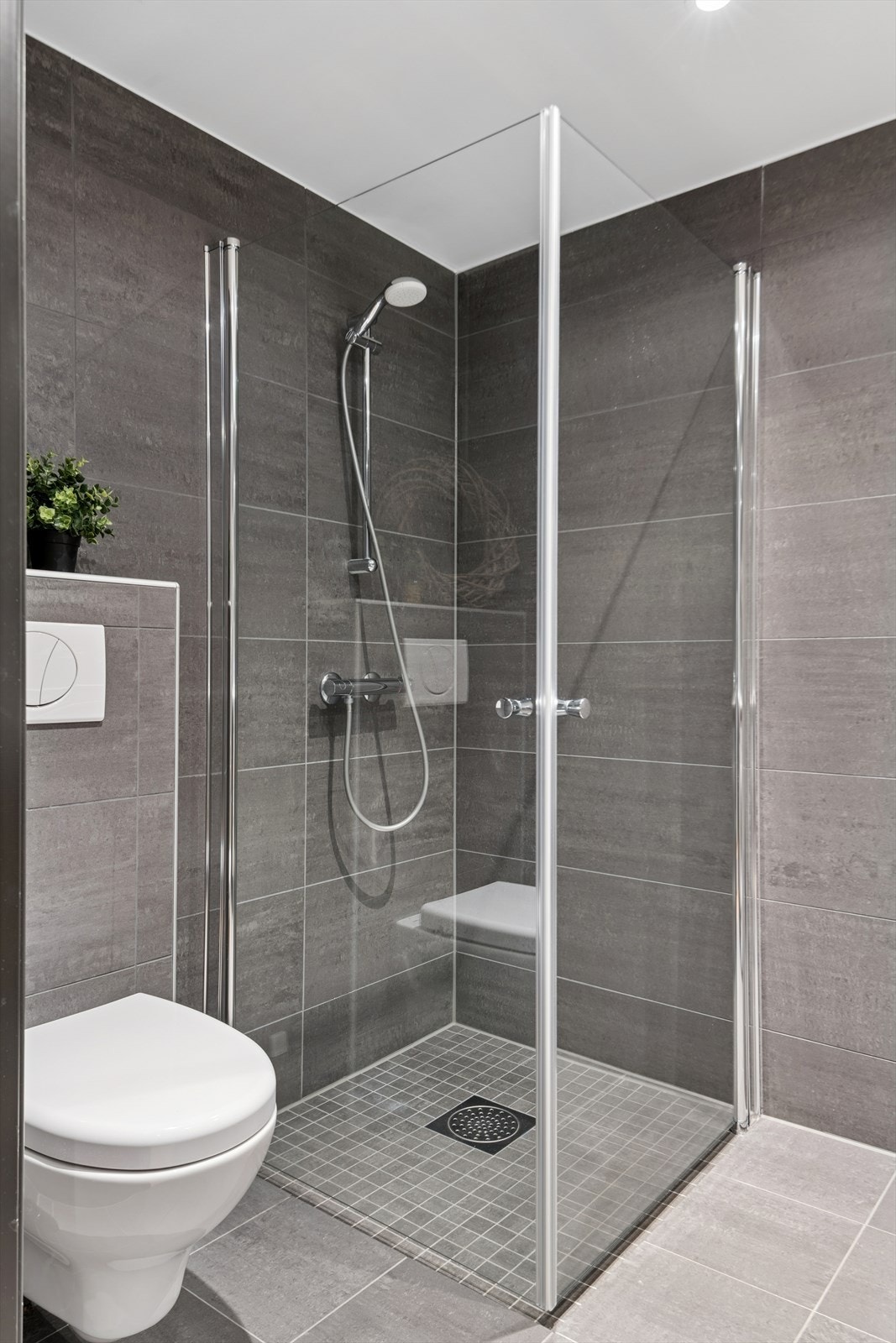 Badet har dusj med innfellbare dører i herdet glass og vegghengt toalett. Galleribilde