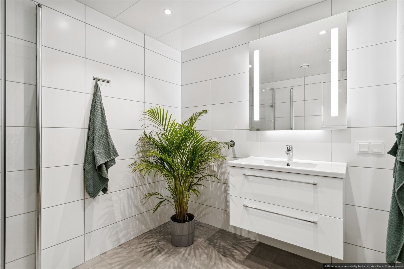 Det 4,9 m² store badet er utstyrt med stilfulle fliser og gjennomtenkt belysning som skaper en innbydende atmosfære. Galleribilde